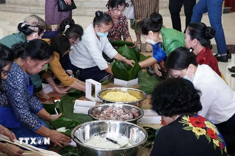 Cựu lưu học sinh Lào tham gia gói bánh chưng. (Ảnh: Phạm Kiên/TTXVN) 
