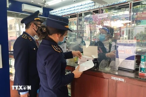 Cục Quản lý thị trường Quảng Ninh kiểm tra hoạt động kinh doanh kit test nhanh và thuốc điều trị COVID-19 tại một cơ sở bán thuốc. (Ảnh: TTXVN phát) 