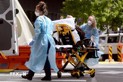 Nhân viên y tế chuyển bệnh nhân COVID-19 tới bệnh viện tại Melbourne, Australia. (Ảnh: AFP/TTXVN) 