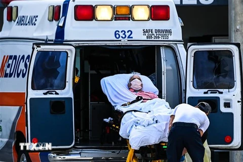 Nhân viên y tế chuyển bệnh nhân COVID-19 tới bệnh viện tại Coral Gables, gần Miami, Mỹ. (Ảnh: AFP/TTXVN) 