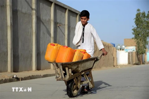 Một em nhỏ chở nước sinh hoạt lấy từ vòi công cộng ở thành phố Kandahar, Afghanistan ngày 22/3/2022. (Ảnh: THX/TTXVN) 