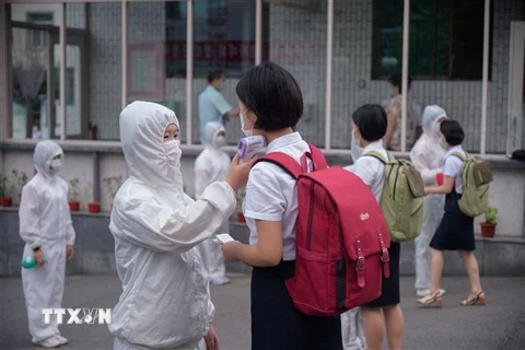 Kiểm tra thân nhiệt nhằm ngăn chặn sự lây nhiễm của dịch COVID-19 tại một trường học ở Bình Nhưỡng, Triều Tiên. (Ảnh: AFP/TTXVN) 
