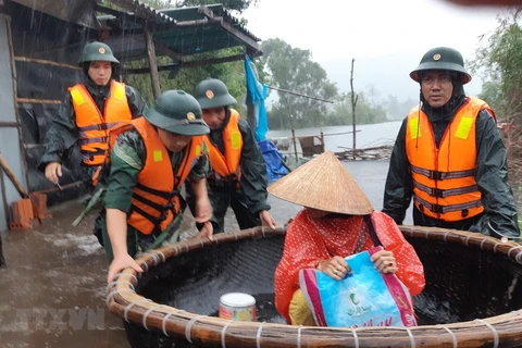 Lực lượng chức năng hỗ trợ người dân ứng phó với mưa lũ. (Ảnh: TTXVN phát) 