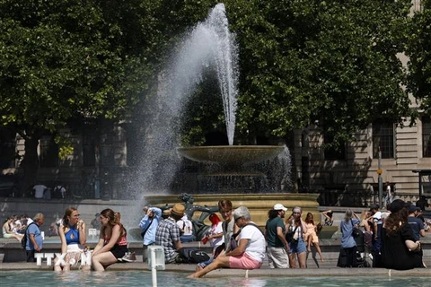 Người dân làm mát tại đài phun nước do nắng nóng gay gắt ở London, Anh ngày 17/6/2022. Theo Văn phòng khí tượng Anh, 50% khả năng nhiệt độ nước này trong ngày 18 và 19/7 sẽ lần đầu tiên vượt 40 độ C. (Ảnh: AFP/TTXVN) 