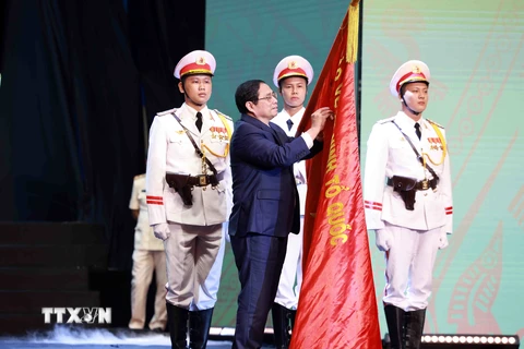 Thủ tướng Phạm Minh Chính gắn Huân chương Hồ Chí Minh lên lá cờ truyền thống của lực lượng Cảnh sát Nhân dân, Bộ Công an. (Ảnh: Phạm Kiên/TTXVN) 