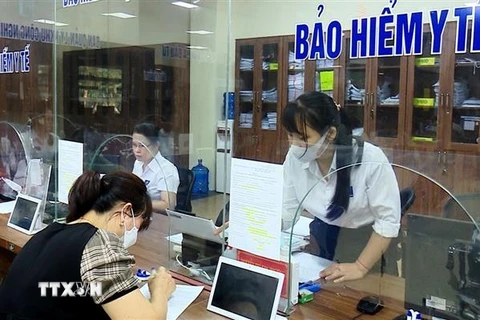 Cán bộ Bảo hiểm xã hội tỉnh Yên Bái hướng dẫn người dân tại Trung tâm Phục vụ hành chính công. (Ảnh: Tiến Khánh/TTXVN) 