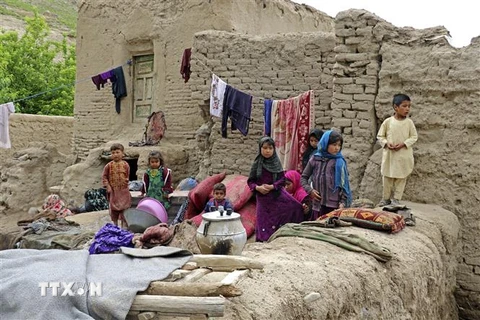 Các em nhỏ ngồi bên cạnh ngôi nhà bị phá hủy do mưa bão tại tỉnh Badghis , Afghanistan ngày 4/5/2022. (Ảnh: THX/TTXVN) 