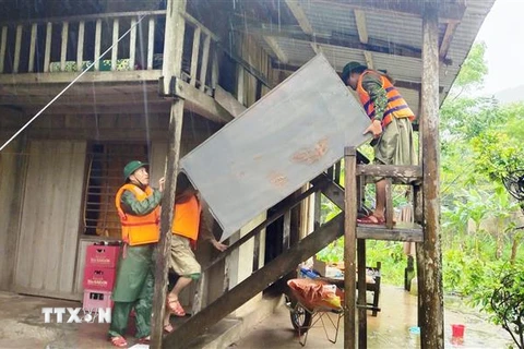 Cán bộ chiến sỹ Đồn Biên phòng Làng Mô, Bộ đội Biên phòng Quảng Bình giúp người dân di dời đồ đạc, tài sản lên chỗ an toàn phòng tránh mưa lũ. (Ảnh: TTXVN phát) 