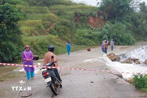 Người dân và lực lượng chức năng xã Măng Ri huyện Tu Mơ Rông (Kon Tum) phối hợp, hỗ trợ cho người và phương tiện đi qua các điểm ngập. (Ảnh: TTXVN phát) 