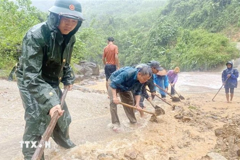 Cán bộ chiến sỹ Đồn Biên phòng Ra Mai, Bộ đội Biên phòng Quảng Bình hỗ trợ cùng nhân dân trên địa bàn khắc phục sạt lở đất đá, khơi thông các tuyến đường trọng yếu. (Ảnh: TTXVN phát) 