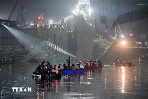 Lực lượng cứu hộ tìm kiếm các nạn nhân và giải cứu những người mắc kẹt tại hiện trường sập cầu treo trên sông Machchu ở Morbi, bang Gujarat, Ấn Độ, rạng sáng 31/10/2022. (Ảnh: AFP/TTXVN) 