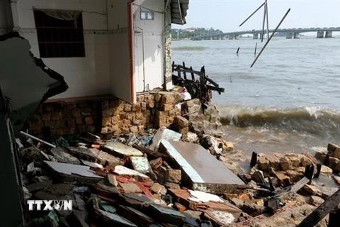 Một ngôi nhà của người dân bị trôi một phần theo những cơn sóng lớn. (Ảnh: Đặng Tuấn/TTXVN) 