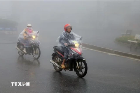 Người dân thị xã Sapa mặc áo mưa tránh rét. (Ảnh: Quốc Khánh/TTXVN)