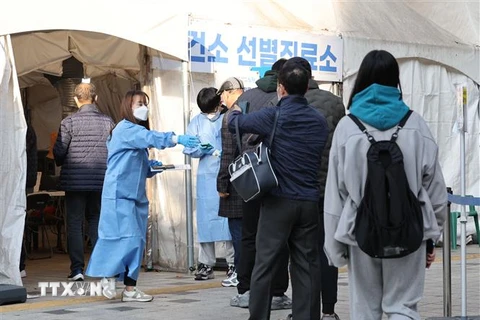 Nhân viên y tế hướng dẫn người dân tại điểm xét nghiệm COVID-19 ở Seoul, Hàn Quốc, ngày 21/11/2022. (Ảnh: Yonhap/TTXVN)