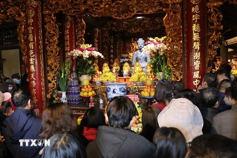 Người dân lễ phật A di đà bằng đá là một trong những bảo vật quốc gia tại chùa Phật Tích. (Ảnh: Thanh Thương/TTXVN)