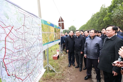 Thủ tướng Phạm Minh Chính xem bản đồ tuyến đường vành đai 4 vùng Thủ đô Hà Nội tại điểm xã Song Phương, huyện Hoài Đức. (Ảnh: Dương Giang/TTXVN)