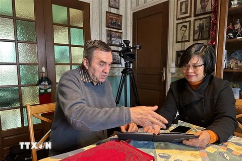 Ông Michel Strachinescu chia sẻ với phóng viên những bức ảnh kỷ niệm khi ông còn là lái xe cho phái đoàn Việt Nam. (Ảnh: Thu Hà/TTXVN)