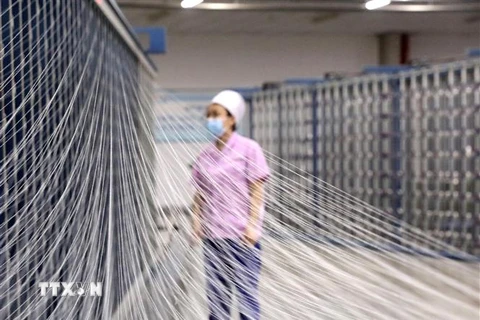 Công nhân làm việc tại một nhà máy dệt ở thành phố Thạch Gia Trang, tỉnh Hà Bắc, Trung Quốc. (Ảnh: THX/TTXVN) 
