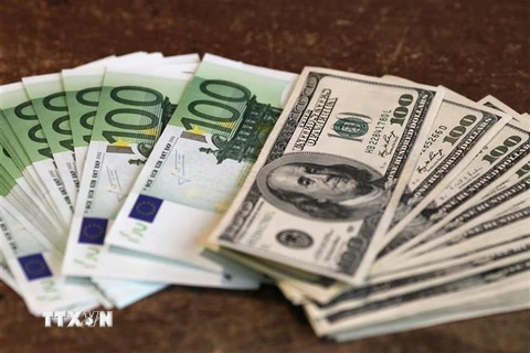 Đồng tiền giấy mệnh giá 100 euro (trái) và 100 USD tại Paris. (Ảnh: AFP/TTXVN)