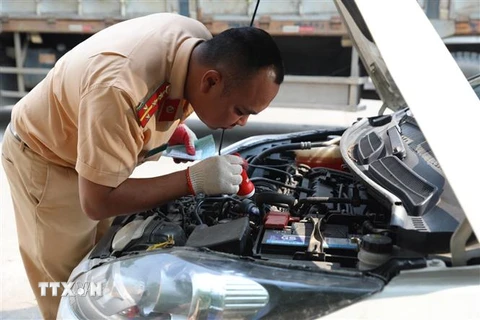 Đại úy công an Đinh Văn Toàn kiểm tra số máy của xe đến đăng kiểm sáng 14/3. (Ảnh: Hoàng Hiếu/TTXVN)