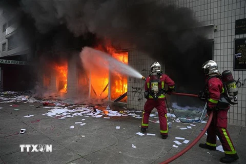 Lính cứu hỏa Pháp dập lửa do người biểu tình bạo loạn phóng hỏa tại văn phòng ngân hàng Credit Mutuel ở Nanterre, ngoại ô Paris, ngày 29/6/2023. (Ảnh: AFP/TTXVN)