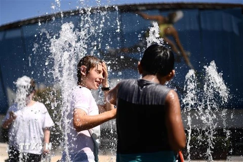 Trẻ em giải nhiệt tránh nóng tại một đài phun nước ở thành phố Melbourne, Australia. (Ảnh: AFP/TTXVN)