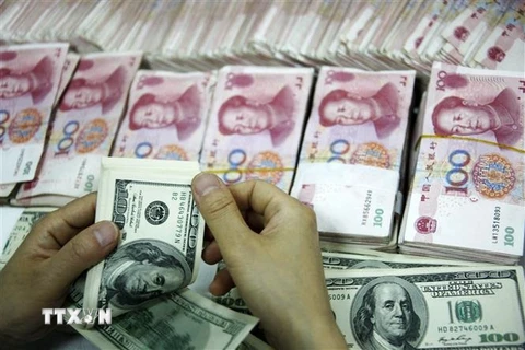Nhân viên kiểm đồng USD và đồng Nhân dân tệ tại một ngân hàng ở tỉnh An Huy, Trung Quốc. (Ảnh: AFP/TTXVN)