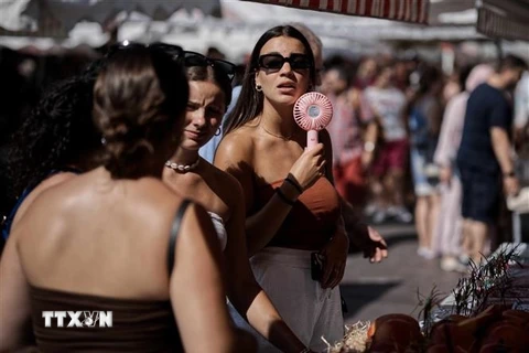 Một phụ nữ dùng quạt điện mini làm mát trong thời tiết nắng nóng gay gắt ở Nice, Pháp, ngày 22/8/2023. (Ảnh: THX/TTXVN)