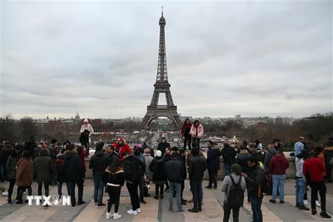 Khách du lịch chụp ảnh bên Tháp Eiffel ở thủ đô Paris, Pháp. (Ảnh: AFP/TTXVN)