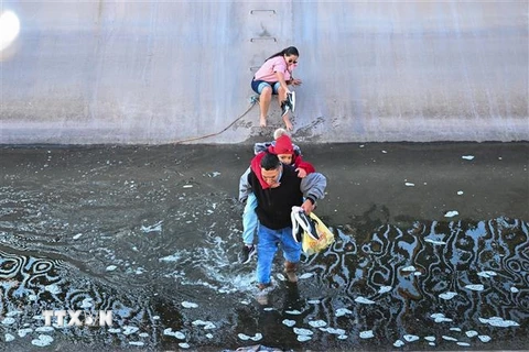 Người di cư vượt qua bức tường biên giới Mỹ-Mexico tại El Paso, Texas, Mỹ. (Ảnh: AFP/TTXVN)