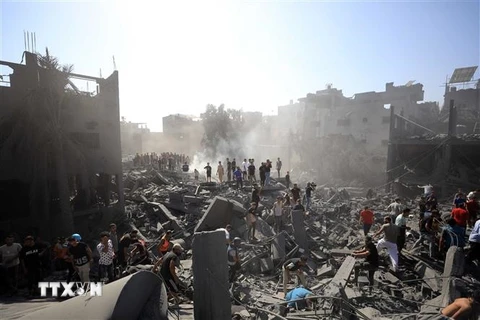 Người dân tìm kiếm người sống sót dưới đống đổ nát tại Dải Gaza sau các cuộc không kích của Israel ngày 26/10/2023. (Ảnh: THX/TTXVN)