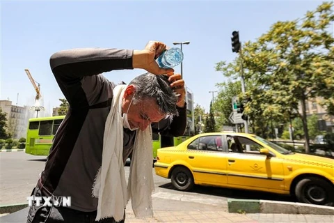 Một người đàn ông đổ nước lên đầu giải nhiệt dưới trời nắng gắt tại Tehran, Iran ngày 11/7/2023. (Ảnh: AFP/TTXVN)