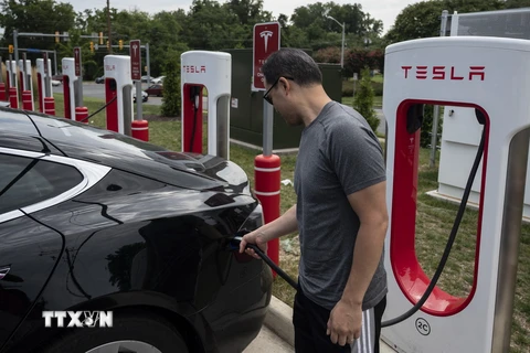 Người dân sạc điện cho ôtô tại một trạm sạc của Tesla ở Arlington, Virginia, Mỹ. (Ảnh: AFP/TTXVN)