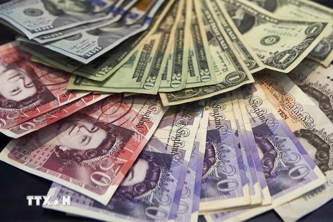 Đồng bảng Anh (phía dưới) và đồng USD tại quầy giao dịch tiền tệ ở London. (Ảnh: AFP/TTXVN)