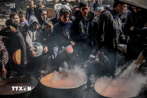 Người dân Palestine nhận thức ăn cứu trợ tại Beit Lahia, phía Bắc Dải Gaza ngày 26/2/2024. (Ảnh: AFP/TTXVN)