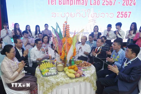 Các đại biểu thực hiện nghi lễ theo phong tục Tết Bunpimay của Lào. (Ảnh: Thu Hằng/TTXVN)