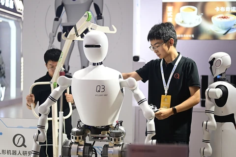 Một nhân viên kiểm tra robot hình người tại Triển lãm Robot Thế giới 2024. (Nguồn: GT)