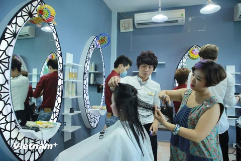 Chị Đào, chủ salon đang tự tay làm tóc cho một khách hàng tên Thu. (Ảnh: PV/Vietnam+)