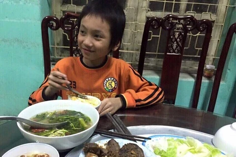 Bé trai được ăn cơm tại trụ sở đội Cảnh sát giao thông số 8. (Ảnh: PV/Vietnam+)