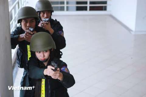 Nữ cảnh sát đặc nhiệm xinh đẹp phối hợp cùng đồng đội tiếp cận mục tiêu trong tình huống giả định các con tin bị khủng bố khống chế. (Ảnh: Minh Sơn/Vietnam+)