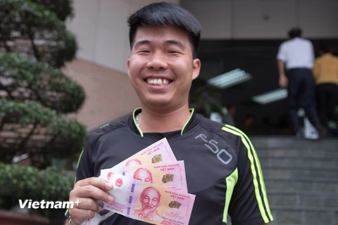Vẻ mặt hạnh phúc khi được sở hữu đồng tiền kỷ niệm. (Ảnh: Minh Sơn/Vietnam+)