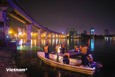 Hàng chục công nhân công ty thoát nước Hà Nội đã được điều động gấp rút vớt cá chết làm sạch hồ Hoàng Cầu. (Ảnh: Minh Sơn/Vietnam+)