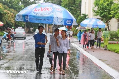 Lực lượng sinh viên tình nguyện đã dùng đến những ô lớn để đưa các thí sinh ra khỏi khu vực thi. (Ảnh: Minh Sơn/Vietnam+)