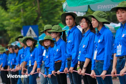 Hình ảnh những sinh viên tình nguyện Đại học Bách khoa lập ‘hàng rào sống’ giúp thí sinh sang đường gây ấn tượng với thí sinh và phụ huynh. (Ảnh: Minh Sơn/Vietnam+)