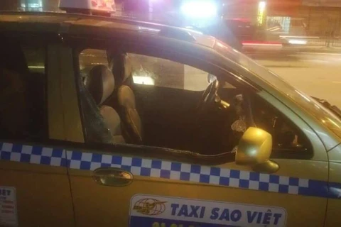 Chiếc xe taxi bị các đối tượng côn đồ đập phá. (Ảnh: PV/Vietnam+)