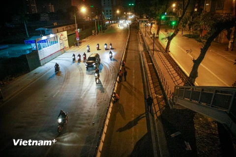 Ngay trong đêm 20 rạng sáng 21/1, hàng chục công nhân được huy động để lắp đặt hàng rào phân cách xe buýt nhanh tại trục đường Láng Hạ - Giảng Võ (Hà Nội). (Ảnh: Minh Sơn/Vietnam+)