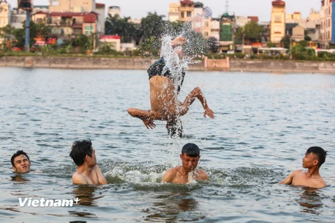 Trước thời tiết nắng nóng kỷ lục ở Hà Nội, người dân đã tận dụng hồ Linh Đàm làm nơi 'giải nhiệt' vì tiện lợi, nhanh chóng và không mất chi phí nào. (Ảnh: Minh Sơn/Vietnam+)