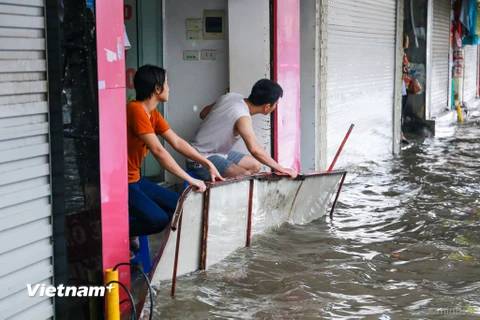 Nhiều cửa hàng trên phố Phạm Ngọc Thạch đã dùng cả biển quảng cáo để chống nước ngập vào nhà sau cơn mưa lớn sáng nay 13/6. (Ảnh: Minh Sơn/Vietnam+)