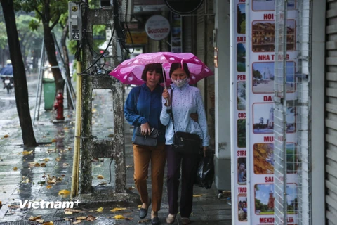 Trong buổi sáng 10/10, những cơn mưa rào kéo theo nhiệt độ giảm mạnh khiến nhiều người dân Hà Nội phải ra đường trong tình trạng lạnh cóng, co ro. (Ảnh: Minh Sơn/Vietnam+)