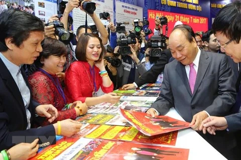 Thủ tướng Nguyễn Xuân Phúc thăm gian trưng bày của Liên Chi hội Nhà báo Thông tấn xã Việt Nam. (Ảnh: TTXVN)